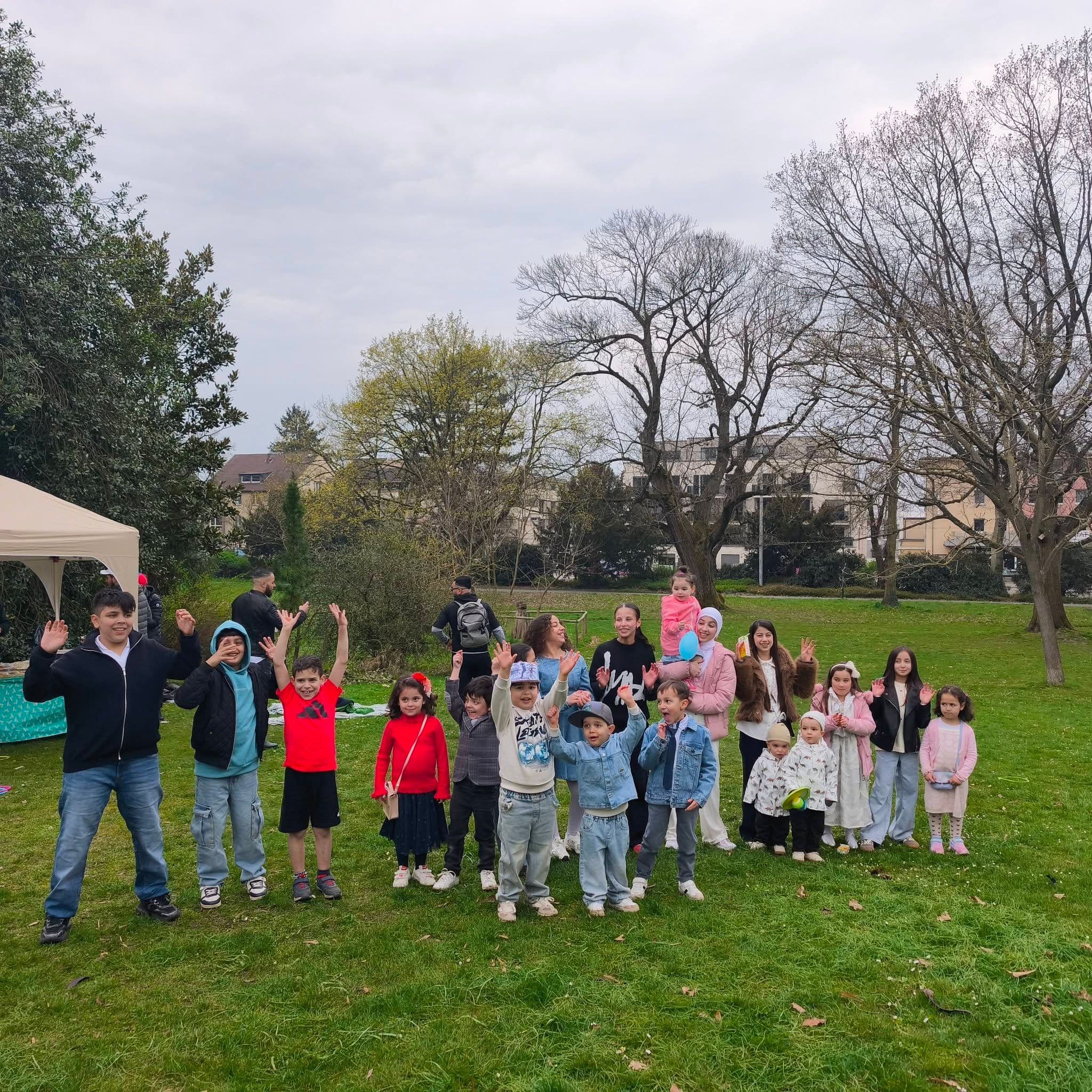 Eine große Gruppe von Familien und Kindern auf einer Wiese im Park