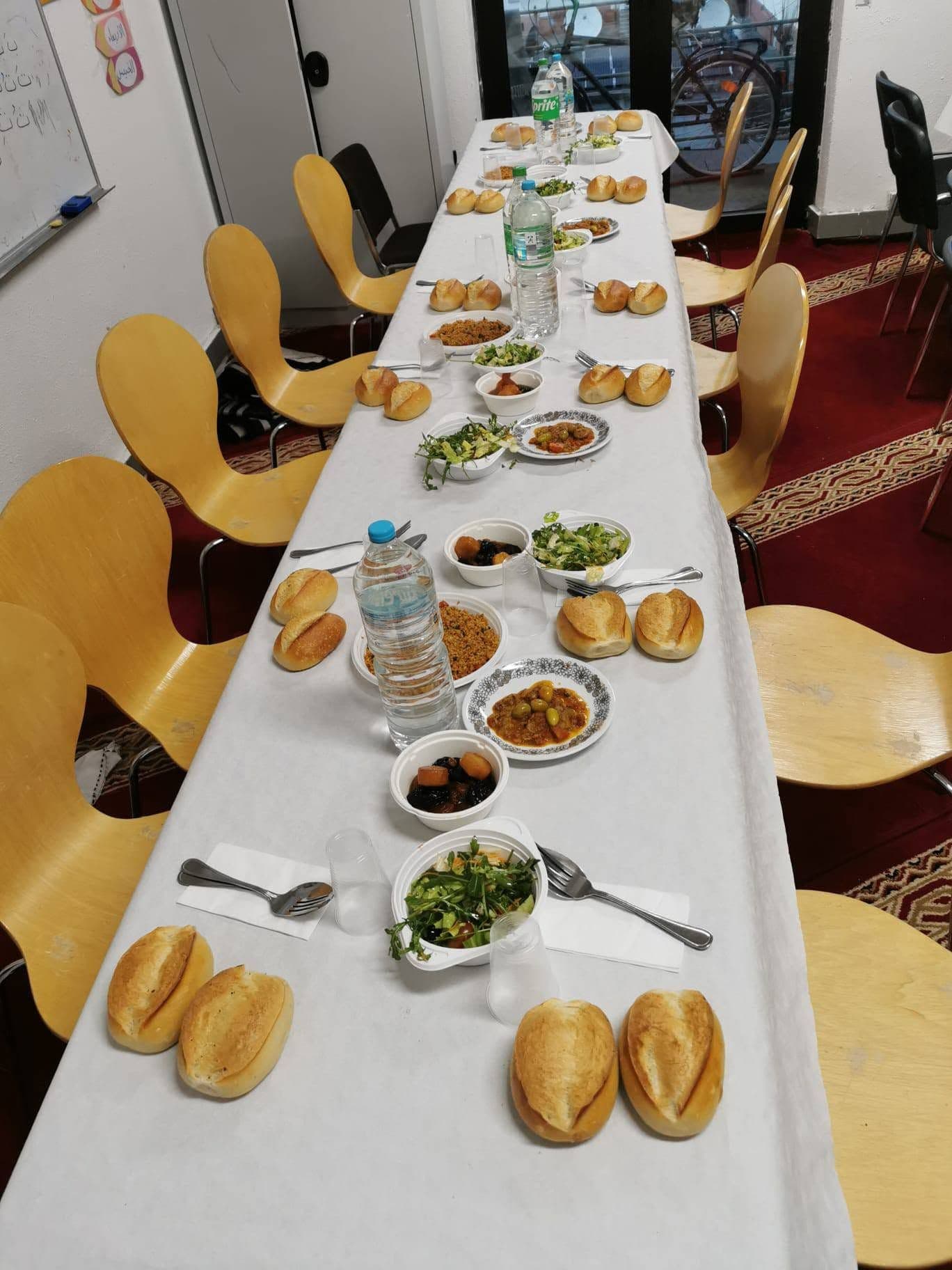 Eine lange, gedeckte Tafel mit Brot, Salaten und Suppe