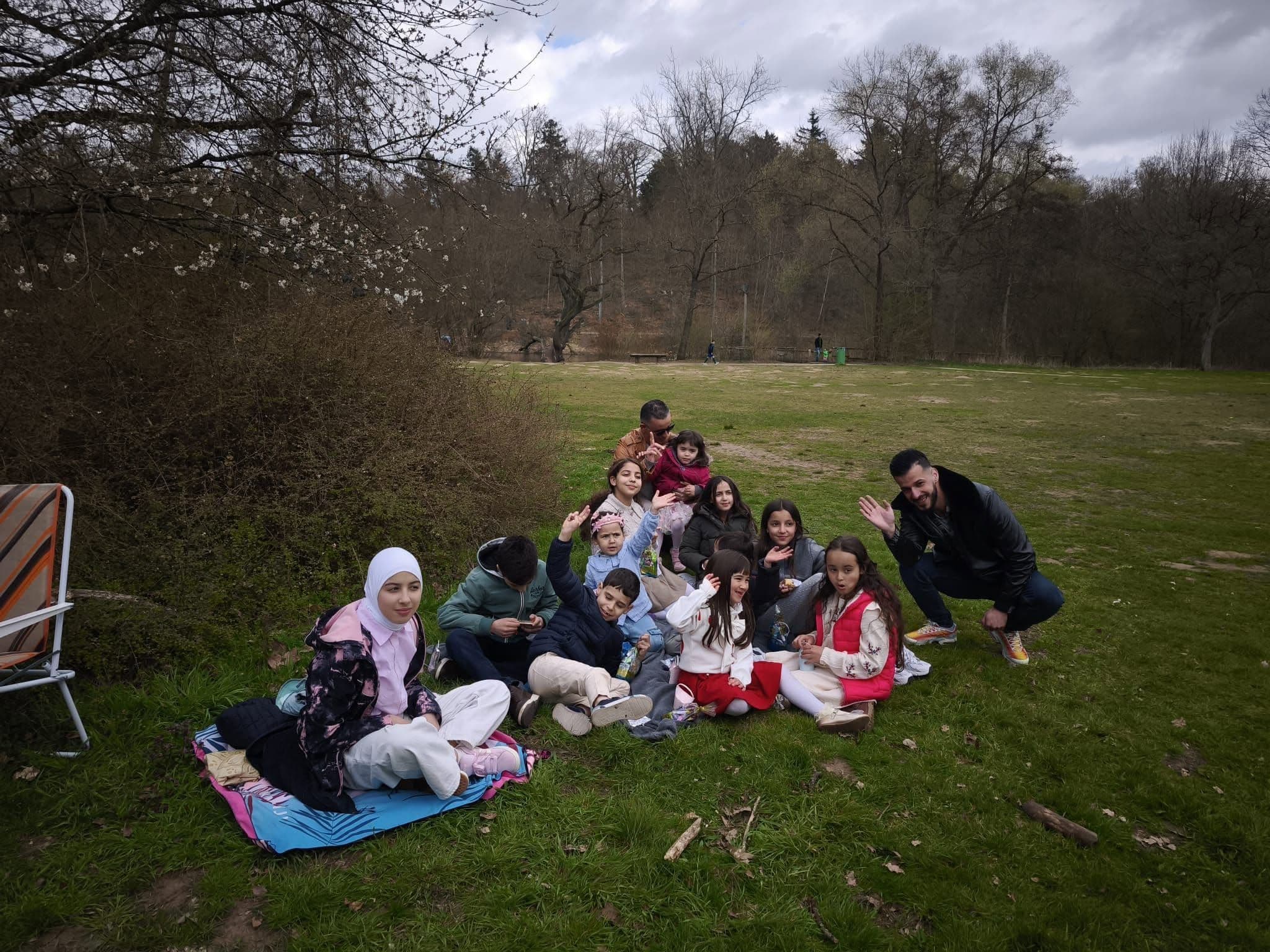 Familien mit Kindern beim Picknick auf einer Decke im Park